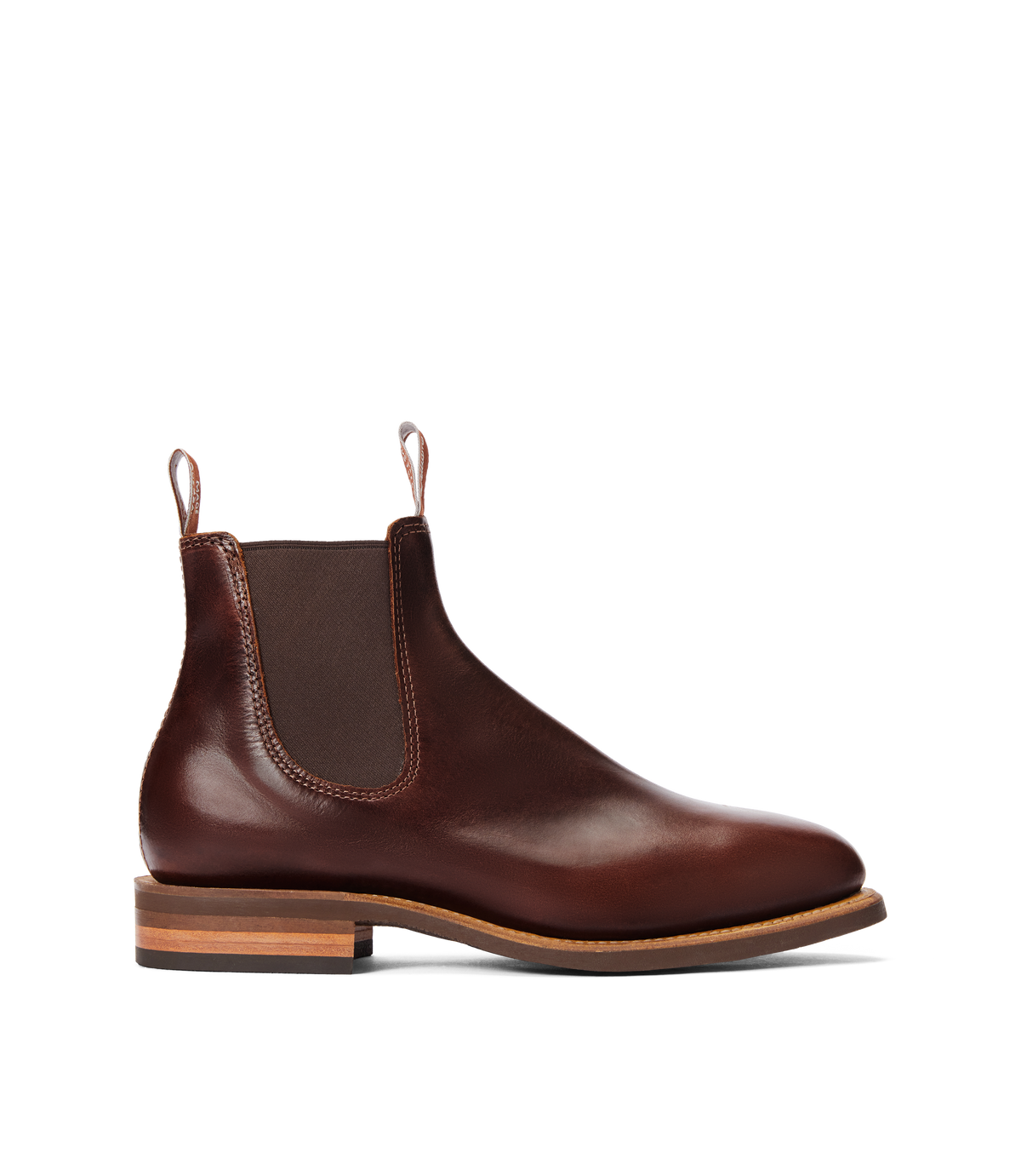 The RM Williams Moriarty Rubber Sole Boot is a brown pull-up leather Chelsea boot with elastic side panels, front and back pull tabs, Goodyear welt construction, and a stacked heel, displayed in profile on a white background.