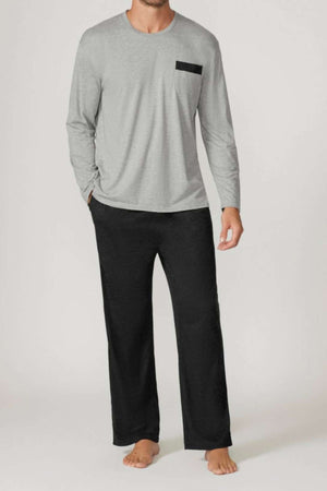 A man stands barefoot against a plain background wearing the Contare Country Bamboo Cotton Long Sleeve Set in light gray with a black chest pocket and loose black pajama pants, highlighting its stylish, breathable loungewear design.