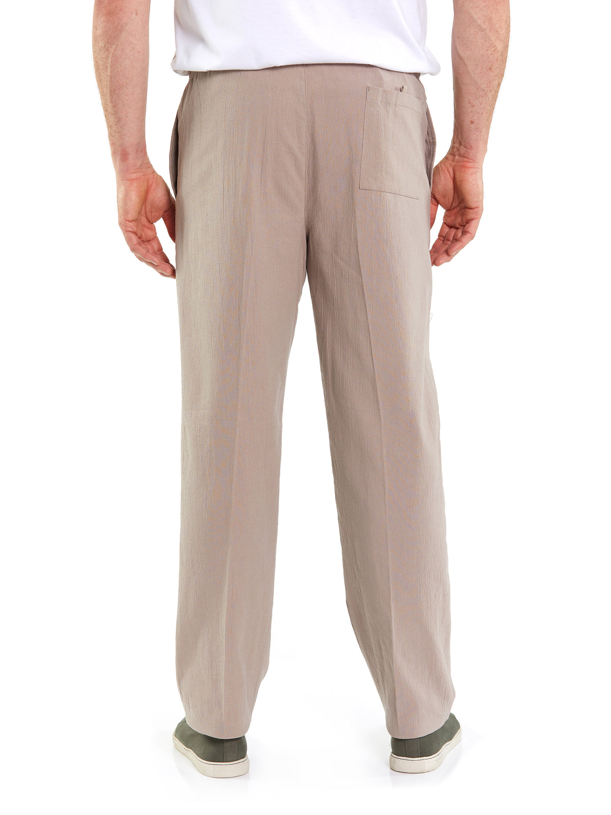 Rear view of a person wearing the Breakaway Crinkle Pants in light brown, featuring an elastic waist and a single pocket on the back right side, paired with a white T-shirt. The person is also sporting green slip-on shoes with white soles. The background is plain white.