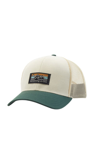 The Billabong Walled A/DIV Trucker hat is beige and green, made from recycled polyester with a mesh back and green brim. It features an embroidered patch with a mountain design, colorful stripes, and "Billabong A/Div" text. The snapback closure allows for an adjustable fit.