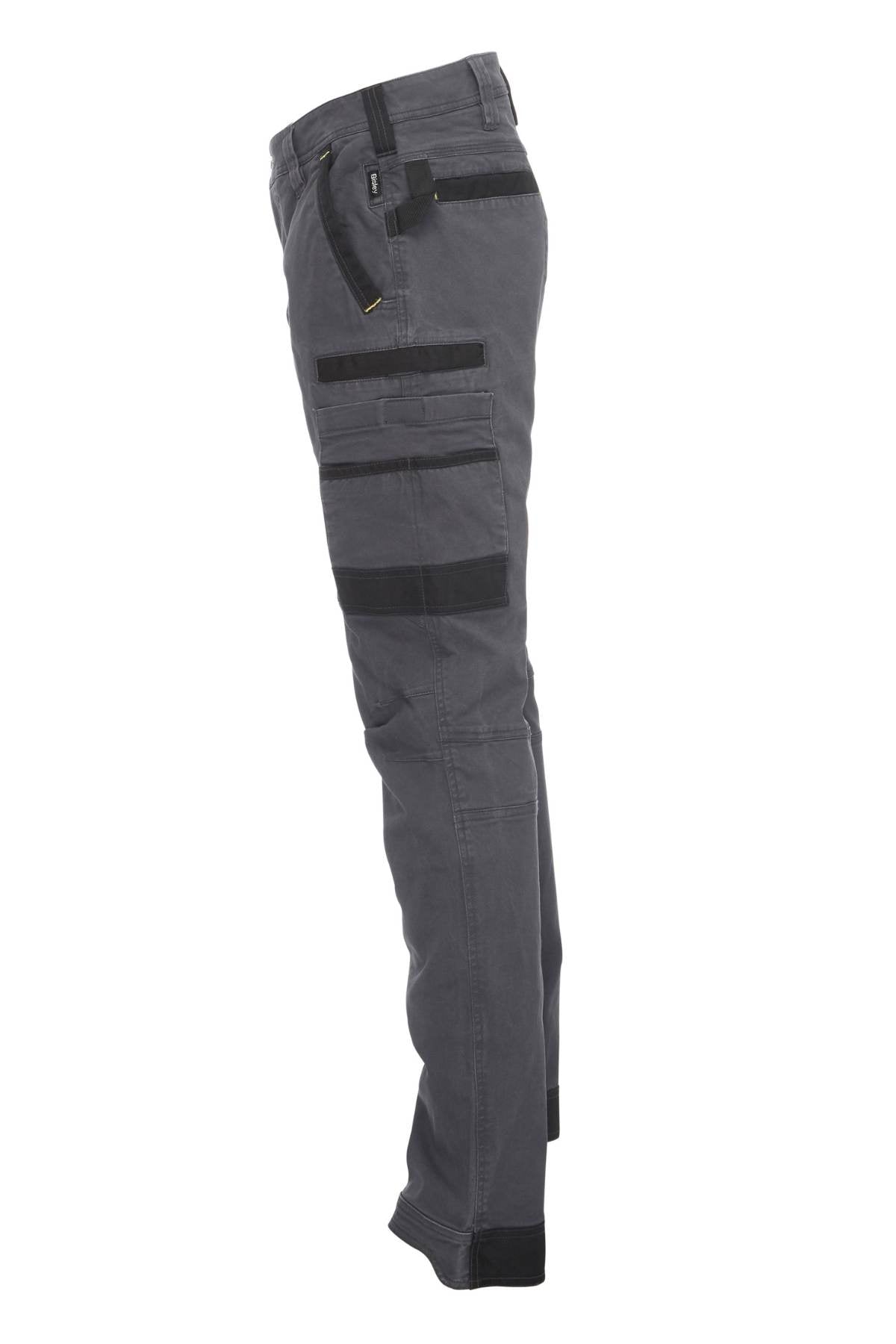 Side view of the Bisley Flex & Move Stretch Utility Cargo Pant in gray, crafted from durable Cordura fabric. These pants feature multiple black cargo pockets and straps, designed for functionality and durability while offering a sleek design ideal for work or outdoor activities.