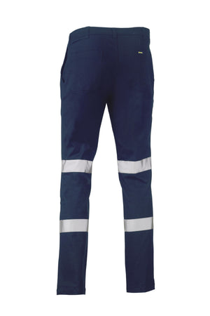 The Bisley Taped Biomotion Stretch Cotton Pant in navy blue is shown from the back, showcasing two reflective silver stripes on each lower leg, back pockets, and UPF 50+ sun protection for enhanced safety and comfort.