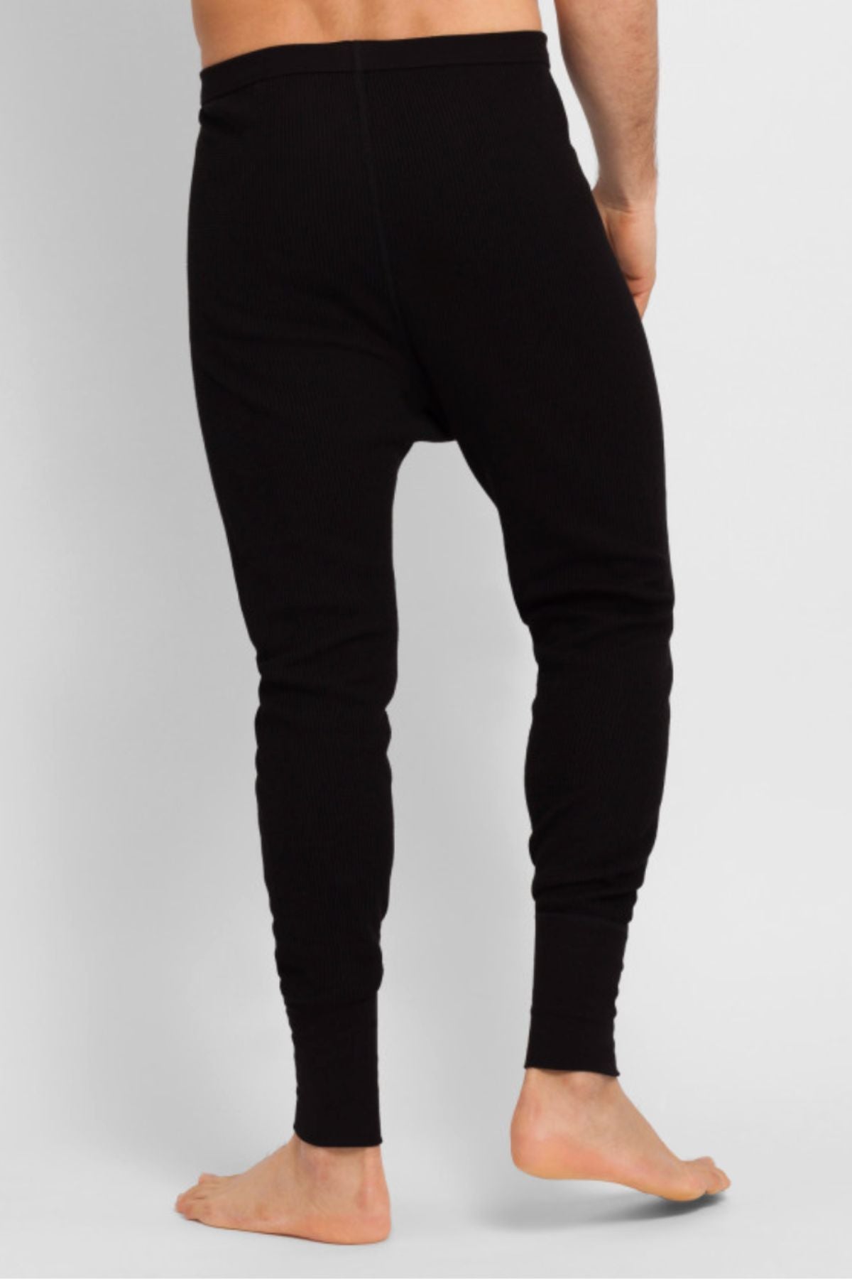 A person stands barefoot, shown from behind, wearing Bonds Aircel Thermal Long Johns in black against a plain, light-colored background.