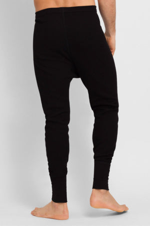 A person stands barefoot, shown from behind, wearing Bonds Aircel Thermal Long Johns in black against a plain, light-colored background.