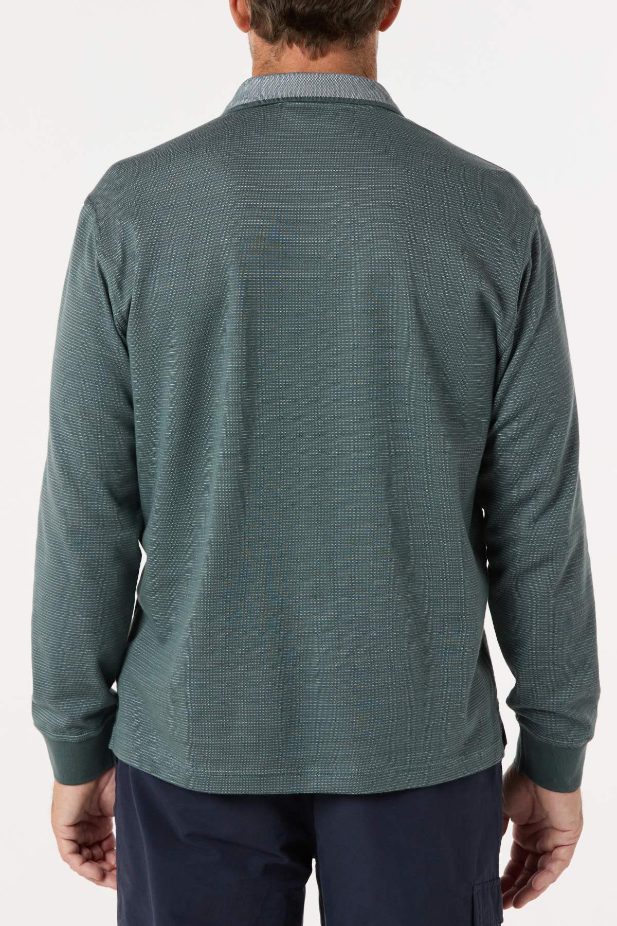 A man is seen from behind wearing a Breakaway Avantee Micro Prima Polo in textured teal with long sleeves, rib knit cuffs, and navy pants. Set against a plain white background, the look combines classic charm with modern style.