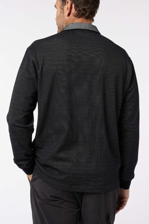 A man stands with his back to the camera, wearing the Breakaway Avantee Micro Prima Polo in black, featuring a subtle texture, contrasting collar, and rib knit cuffs. This versatile long-sleeve piece is set against a plain white background.