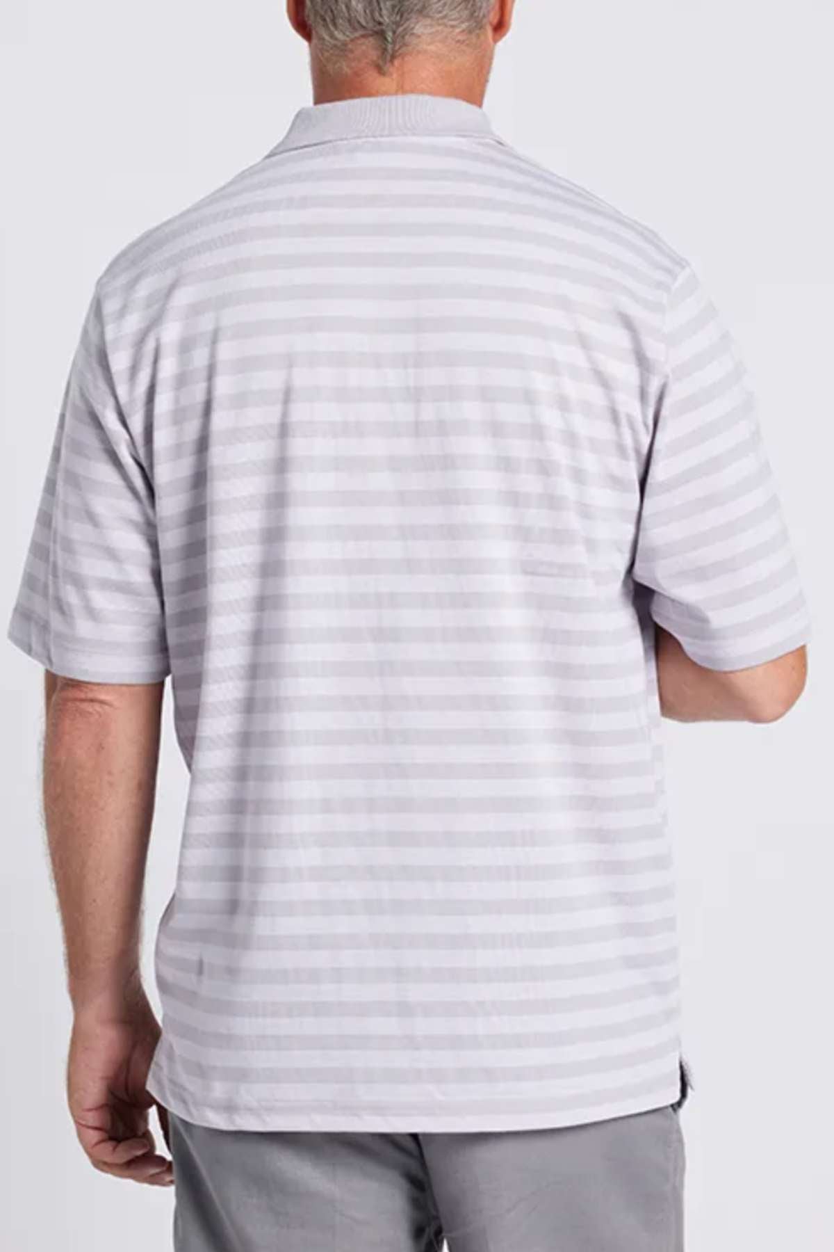 A man is standing with his back to the camera, dressed in a stylish and comfortable light gray Breakaway Brady Kinnersly Polo featuring a contrast rib knit collar, paired with gray pants. The background is plain white.