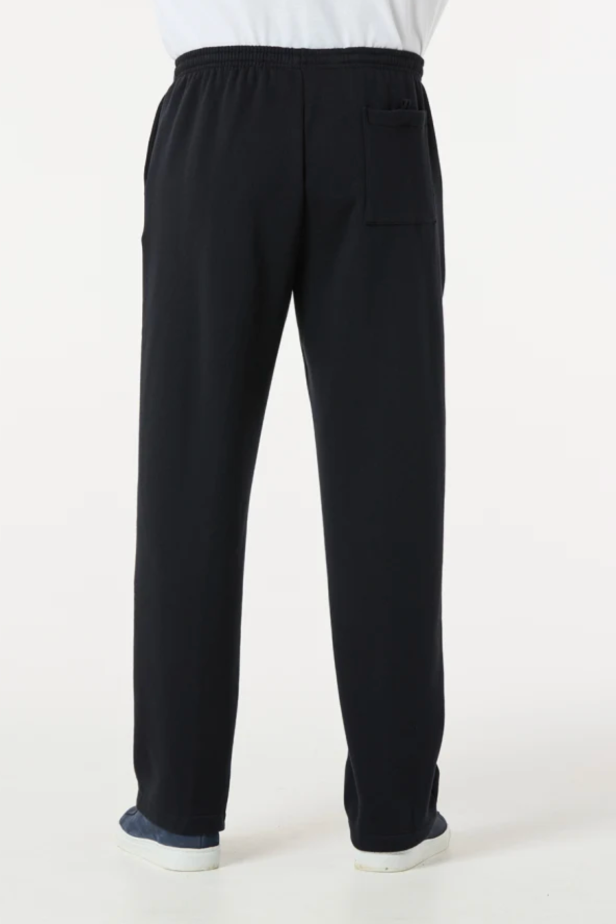 A person is seen from behind wearing Breakaway Classic Snowy Mt Fleece Pant—loose-fitting black pants with an elastic waistband and back pocket, straight to the ankles, styled casually with dark shoes.