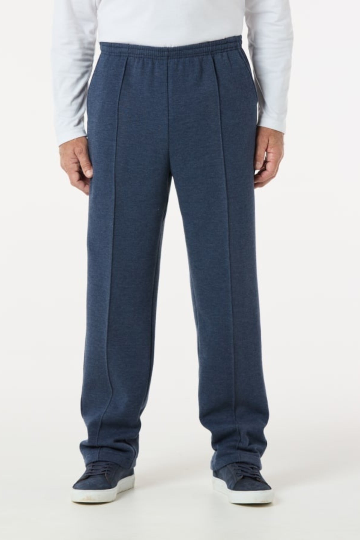 Wearing a white long-sleeve shirt and Breakaway Classic Snowy Mt Fleece Pant in relaxed blue with an elasticated waist and front seams, paired with matching blue sneakers, a person stands against a plain white background.