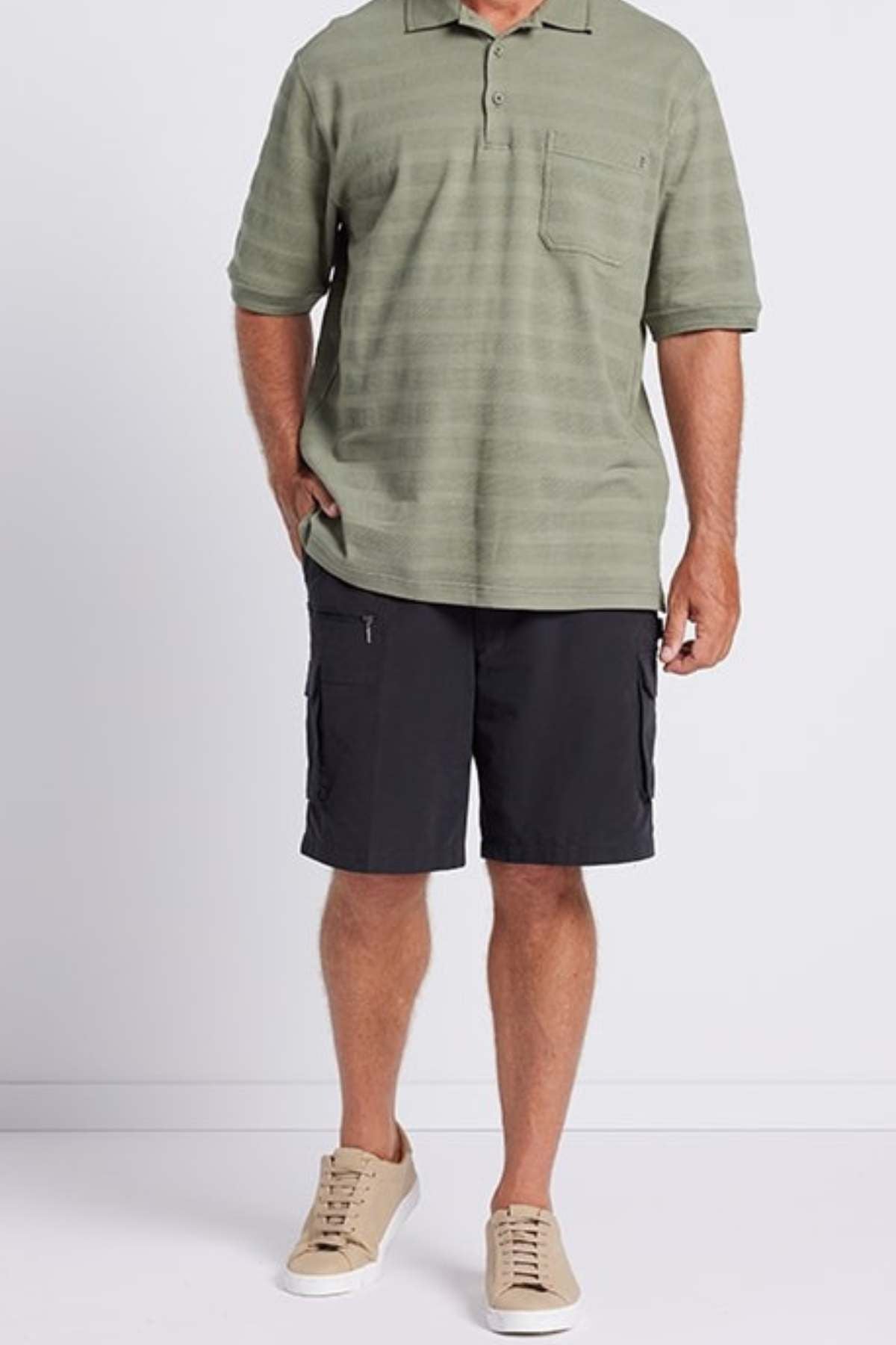A man wearing a Breakaway Emil Polo in olive green with self-jacquard stripes, paired with dark gray cargo shorts and beige sneakers, stands against a plain white background.