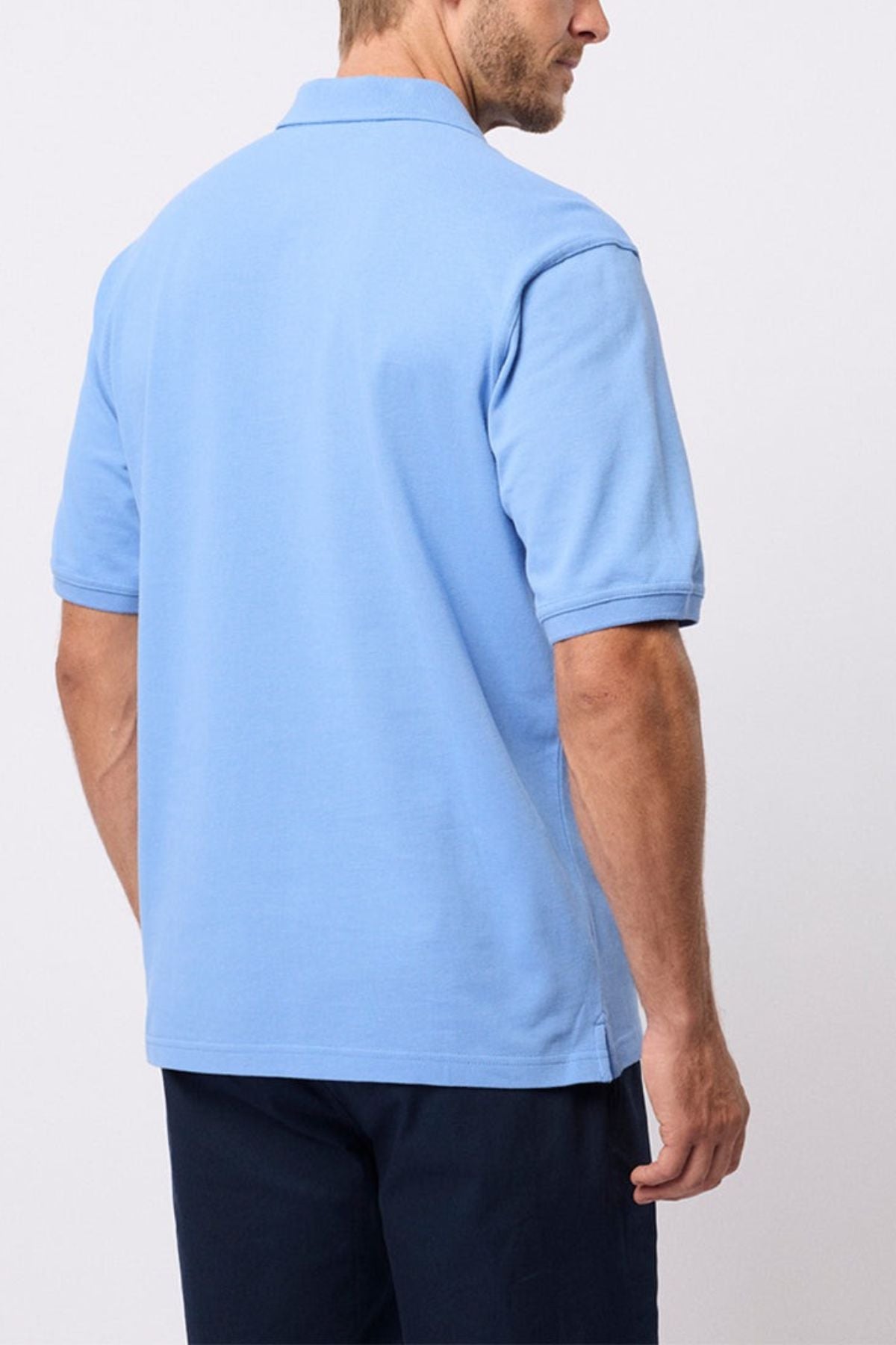 A man is shown from the back, standing against a plain white background, wearing the Breakaway Fraser Cotton Pique Polo in light blue and dark pants.