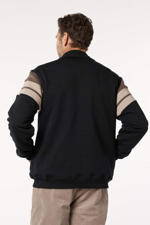 A man faces away from the camera, wearing a Breakaway Henrich Snowy Mt Fleece Half Zip with wide sleeve stripes and light pants, against a plain white background.