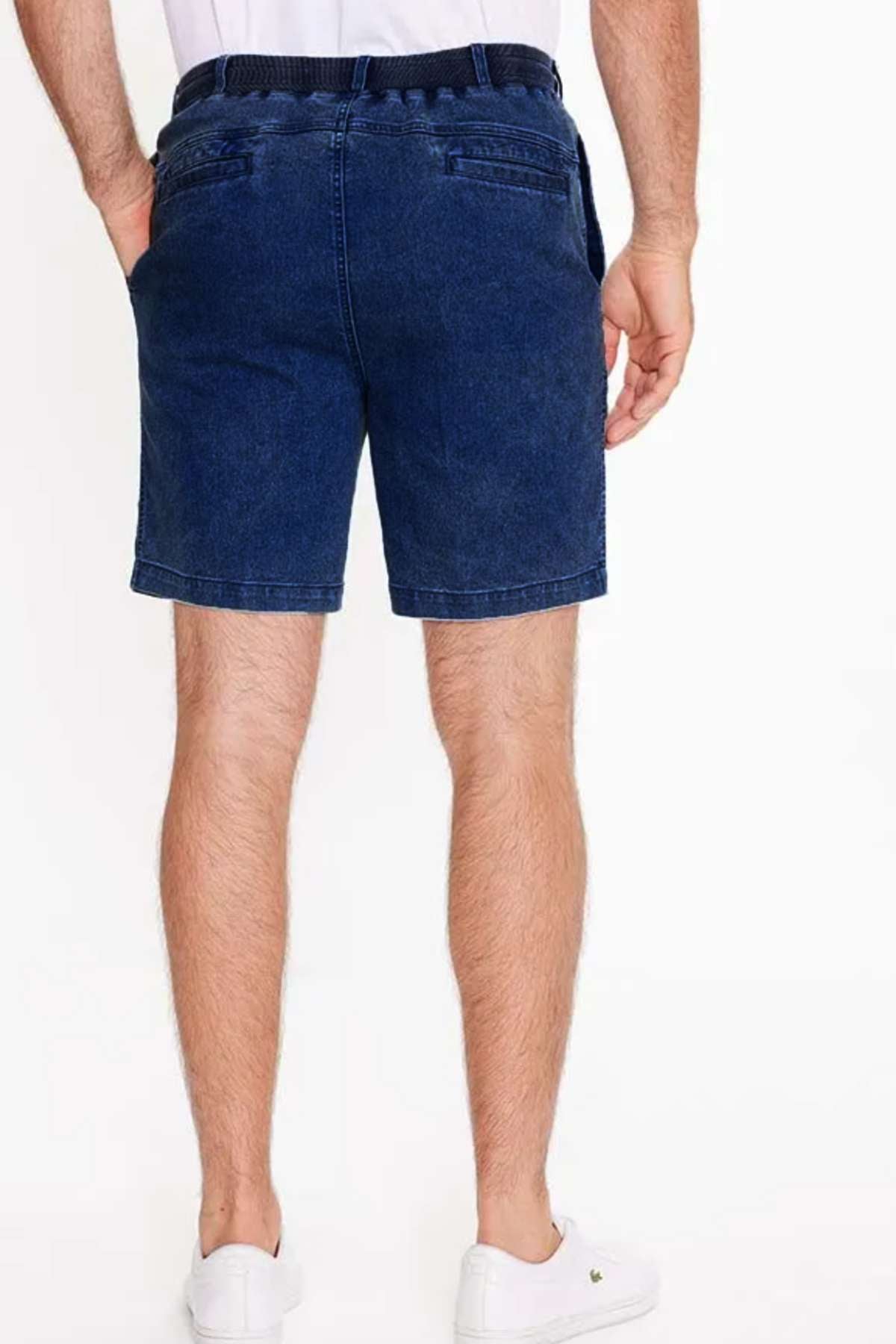 Rear view of a person in Breakaway Intense Denim Short, featuring a fully elasticated waistband and pockets, garment dyed mid-blue denim with a dark belt, paired with white slip-on shoes against a plain white background.