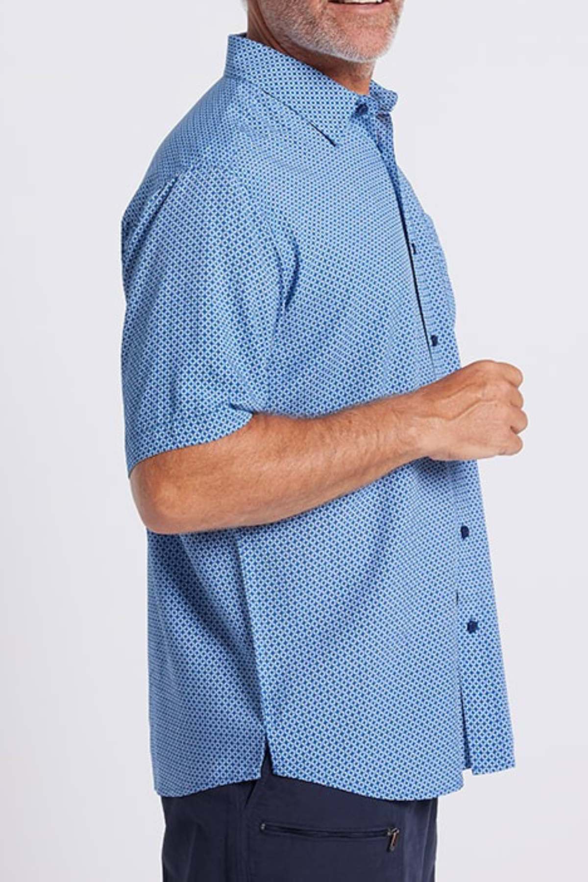 A man stands sideways and smiles, wearing the Breakaway Kre Bamboo Shirt—a light blue, short-sleeve shirt with a subtle dark blue geometric pattern. Its soft touch fabric is ideal for summer. The background is plain white.