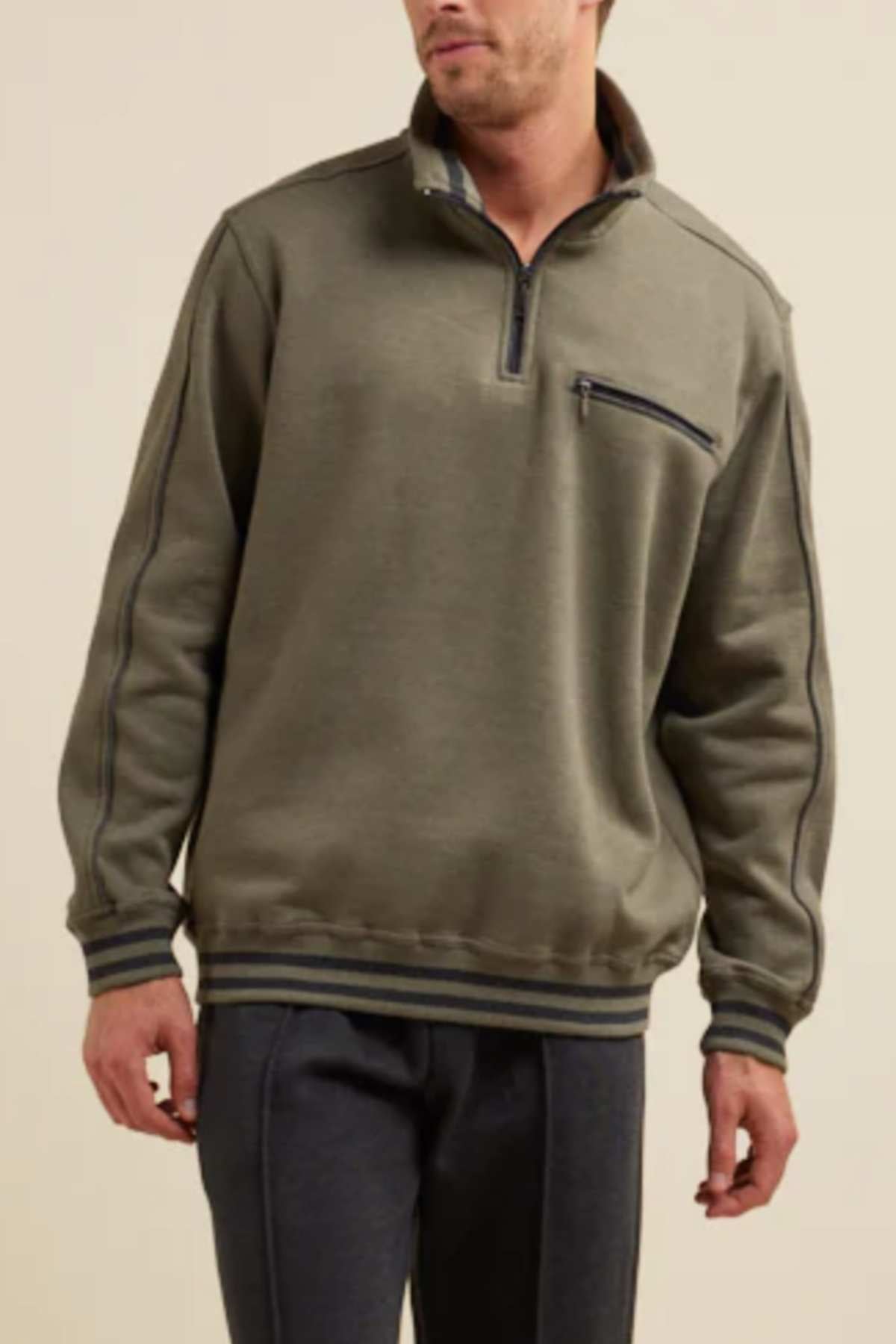 A person is wearing a Breakaway Kyler Snowy Mt Fleece Half Zip, an olive green sweatshirt with a zippered chest pocket, made from soft and warm fleece. The winter-friendly design features dark ribbed cuffs and hem, with dark stitched seams on the sleeves and body. The individual is also wearing dark pants.