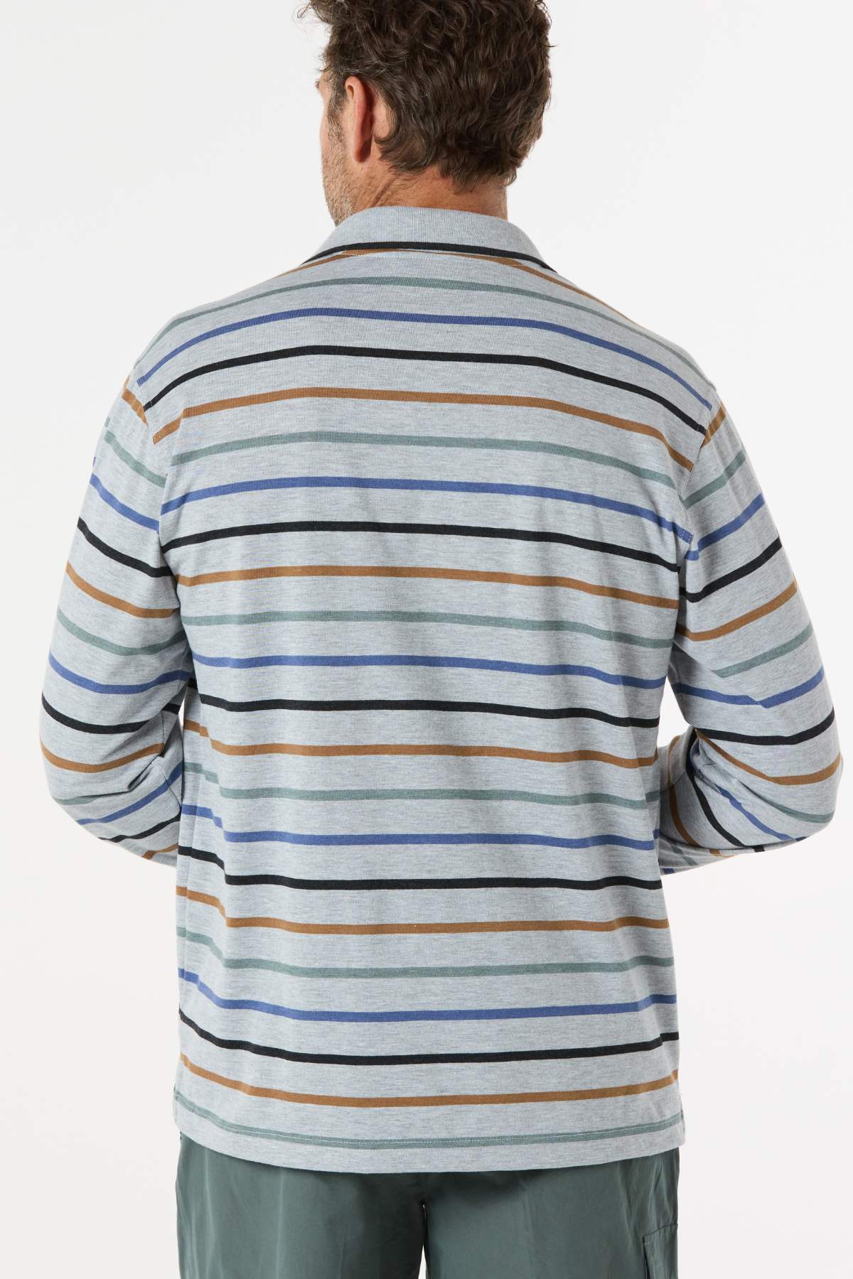 A man with short curly hair, seen from the back, wears a Breakaway Lendel Kinnersly Polo with blue, brown, and black stripes and rib knit cuffs, paired with green pants. The background is plain white.