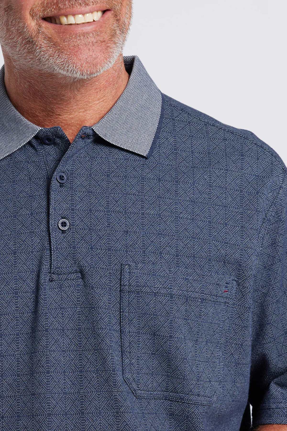A smiling man with a gray beard wears the Breakaway Rye Micro Prima Polo, showcasing its blue Birdseye check, chest pocket, and contrasting collar. Only his lower face and upper torso are visible.