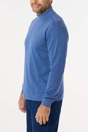 A man stands sideways, smiling slightly, wearing the Breakaway Skivvy—a classic polyester-cotton top—paired with matching blue pants. The winter wear outfit is displayed against a neutral white background.