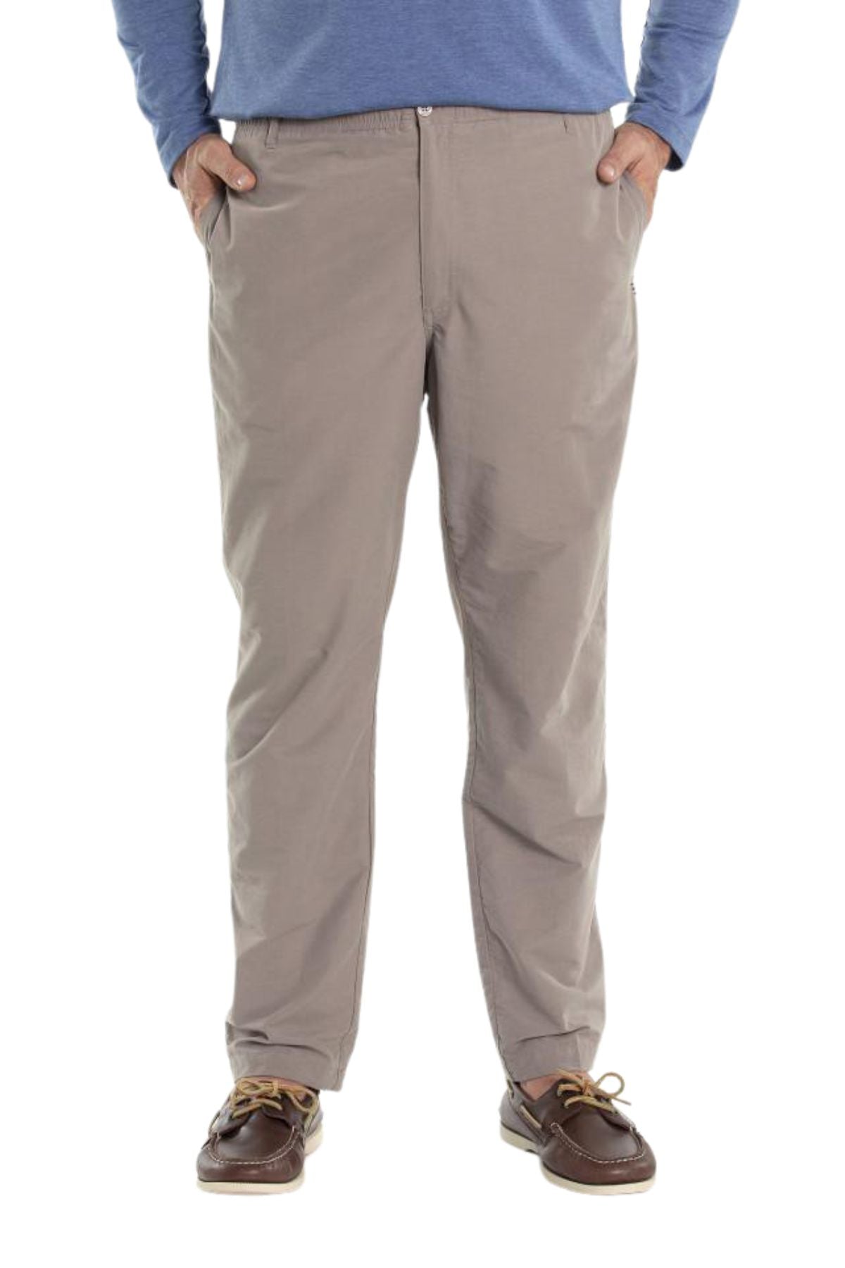 A person wears Breakaway Woodbury Pull On Pants in light brown with an elastic waist, a blue long-sleeve shirt, and brown boat shoes, standing hands-in-pockets against a white background.
