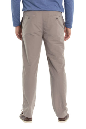 Someone is standing with their back to the camera against a plain white background, wearing Breakaway Woodbury Pull On Pants in light brown with an elastic waist, a blue long-sleeve shirt, and brown shoes.