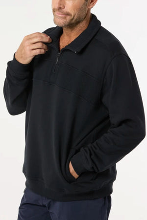 A man wearing the Breakaway Zed Snowy Mt Fleece Half Zip, with cosy fleece lining, stands against a plain light background, one hand in his pocket and the other touching his collar.