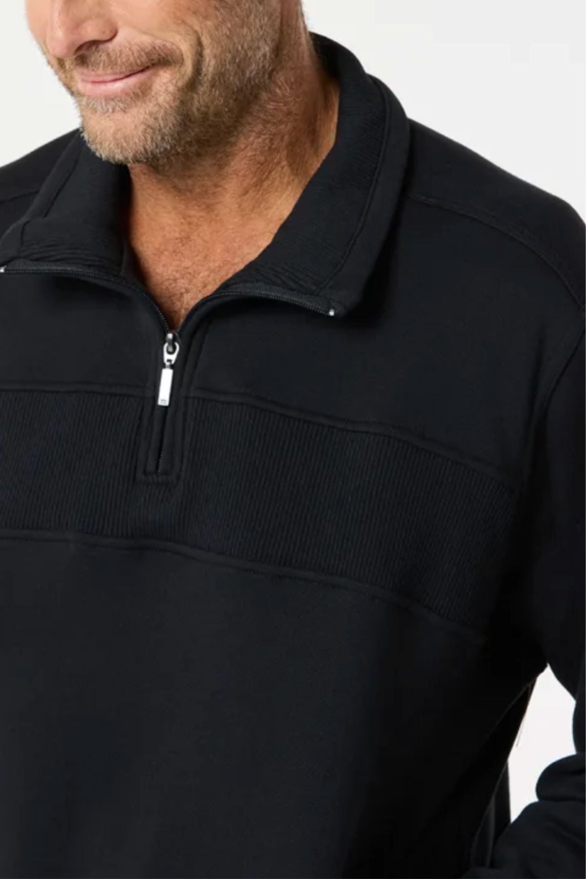 A man with light skin and facial stubble wears the Breakaway Zed Snowy Mt Fleece Half Zip, a classic black pullover with a ribbed chest and half zip placket. He is shown from the shoulders up, slightly smiling against a plain light background.