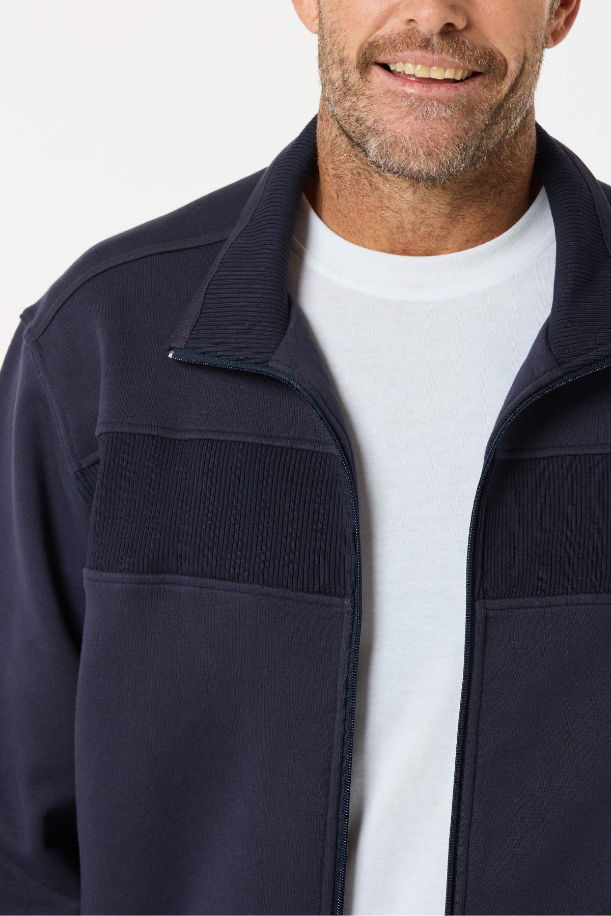 A man smiles in a Breakaway Zed Snowy Mt Fleece Jacket over a white t-shirt. The photo, cropped from shoulders to chin, highlights the jacket's casual comfort—ideal for winter layering.