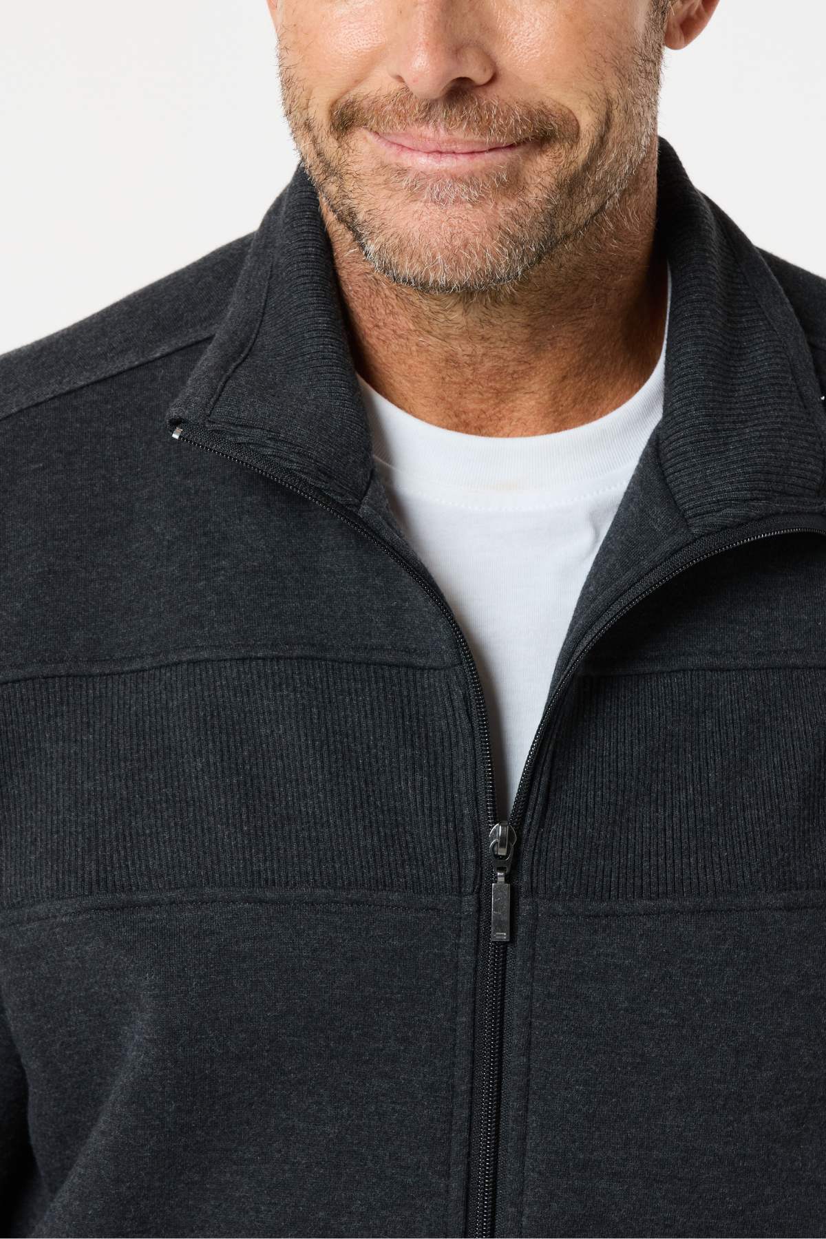 A man wears the Breakaway Zed Snowy Mt Fleece Jacket over a white t-shirt, smiling slightly. Only his lower face and upper torso are visible, highlighting his cozy winter style.