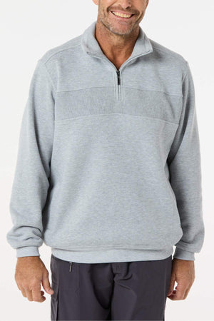 A smiling man wears a light gray Breakaway Zed Snowy Mt Fleece Half Zip with ribbed chest detailing and dark pants, standing against a plain white background.