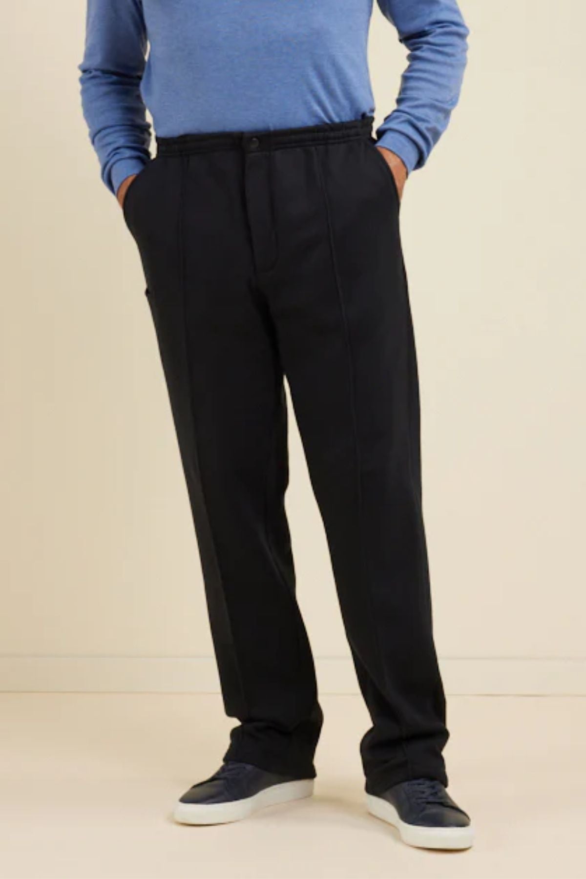 Wearing Breakaway Pocket Snowy Mt Fleece Pants with an elastic waist, a blue long-sleeve shirt, and navy sneakers, a person stands hands-in-pockets against a plain light background.