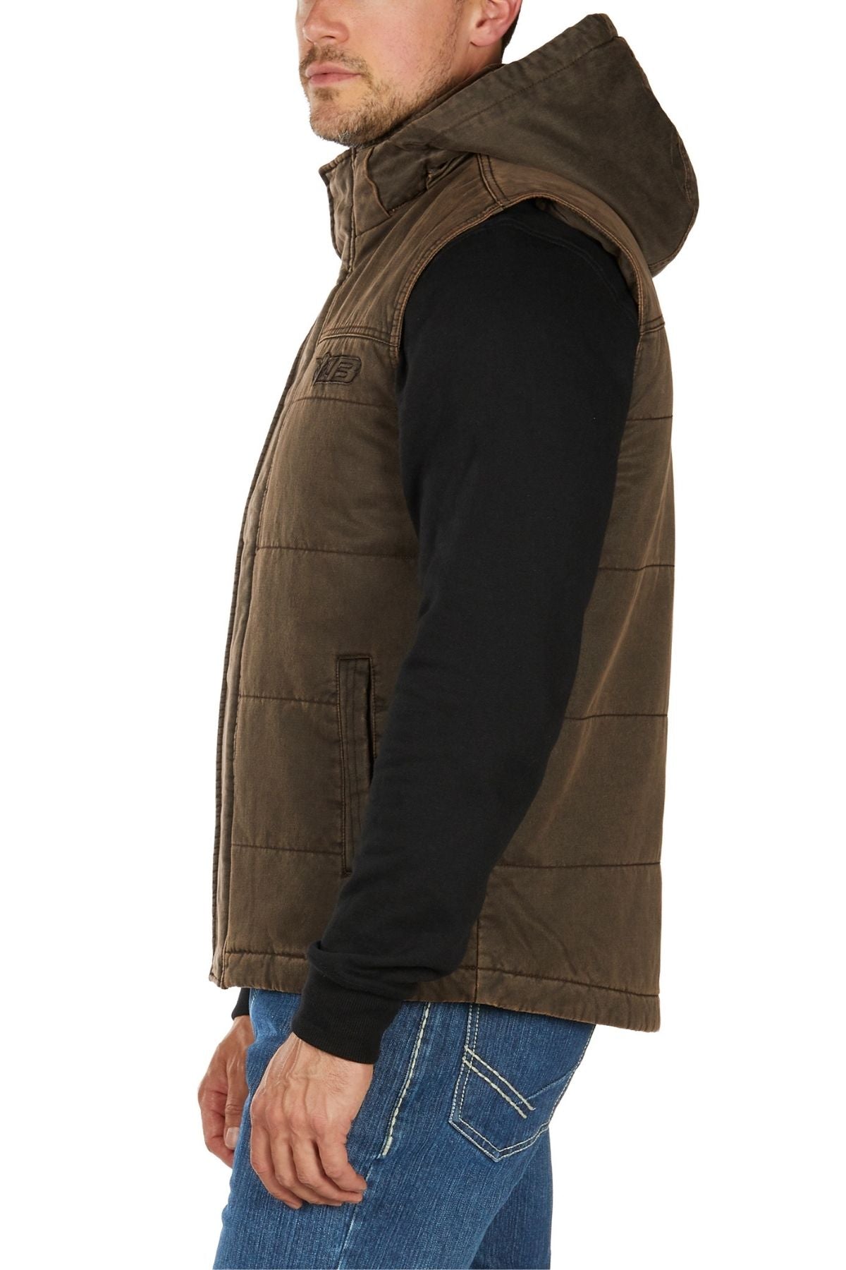 A man wearing the Bullzye Canon Vest over a black long-sleeve shirt and blue jeans stands sideways against a white background.