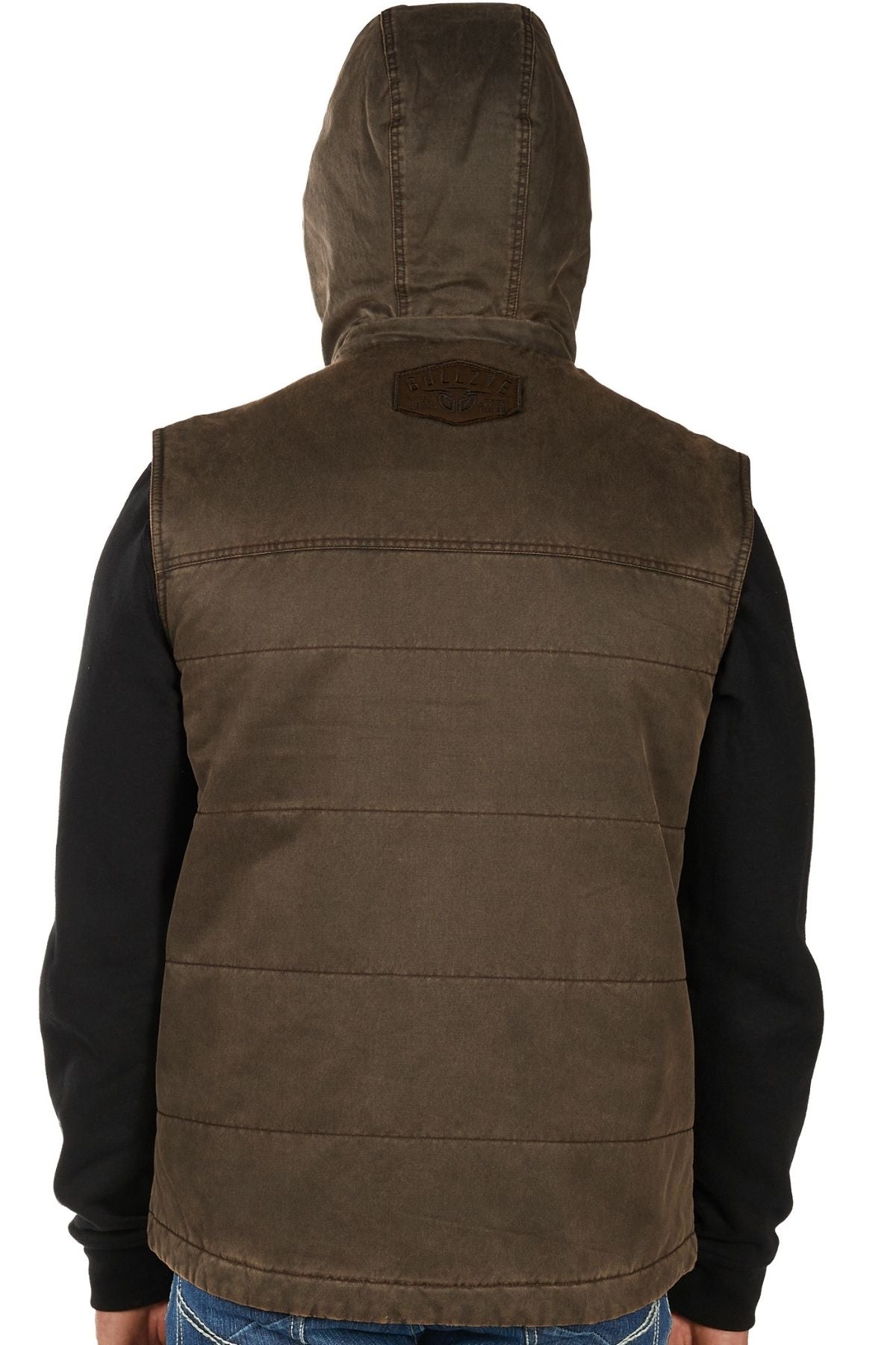 A person is seen from the back wearing the Bullzye Canon Vest—a brown quilted, hooded vest with a small patch near the shoulders—over a black long-sleeve shirt. The hood is up.