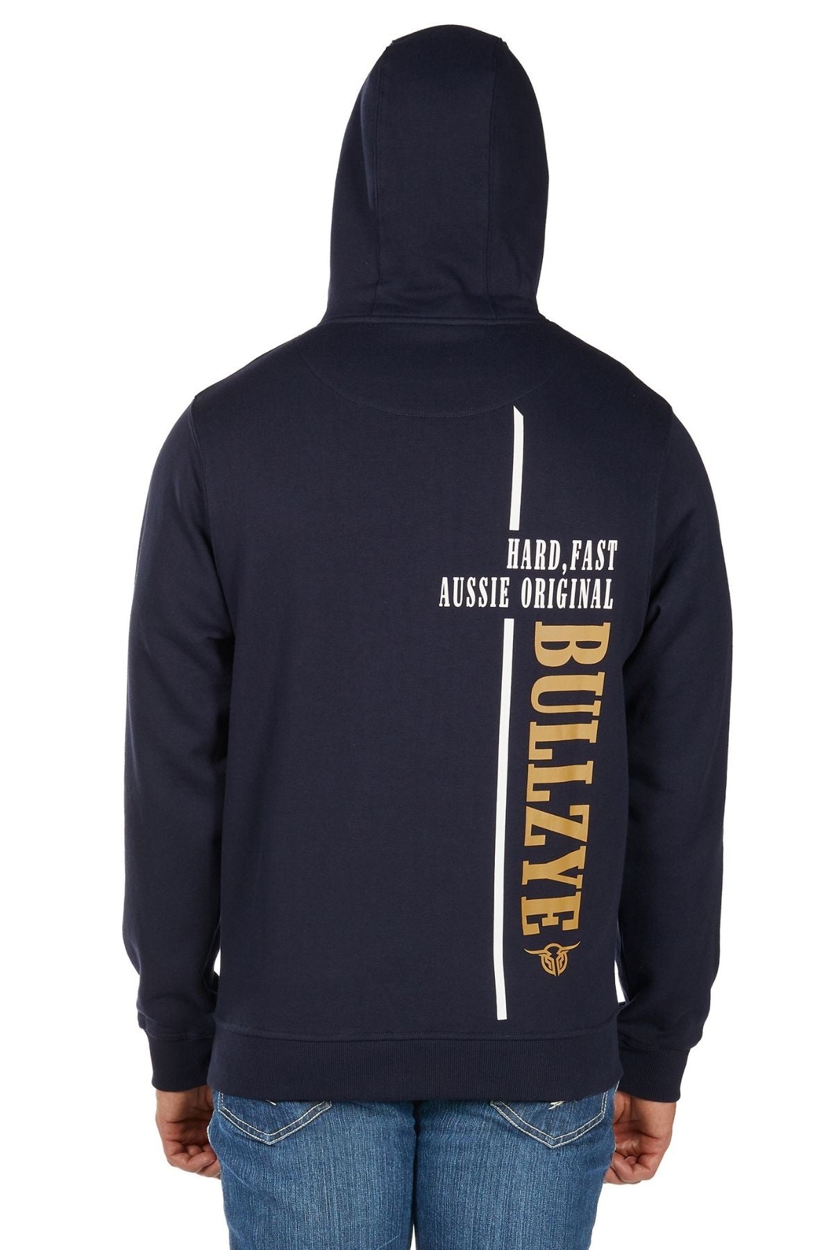 Someone wearing blue jeans and a navy Bullzye Hardy Zip Up Hoodie with the hood up. The hoodie’s back features white and gold "HARD, FAST AUSSIE ORIGINAL BULLZYE" text and a vertical white line.