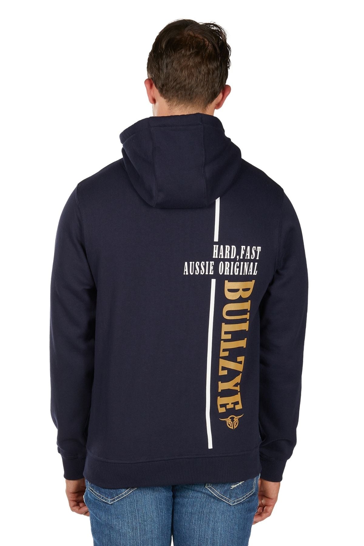 A person wearing the Bullzye Hardy Zip Up Hoodie in navy, hood up and seen from the back. The hoodie displays bold white and yellow text: "HARD, FAST AUSSIE ORIGINAL" and "BULLZYE." They are also wearing blue jeans.