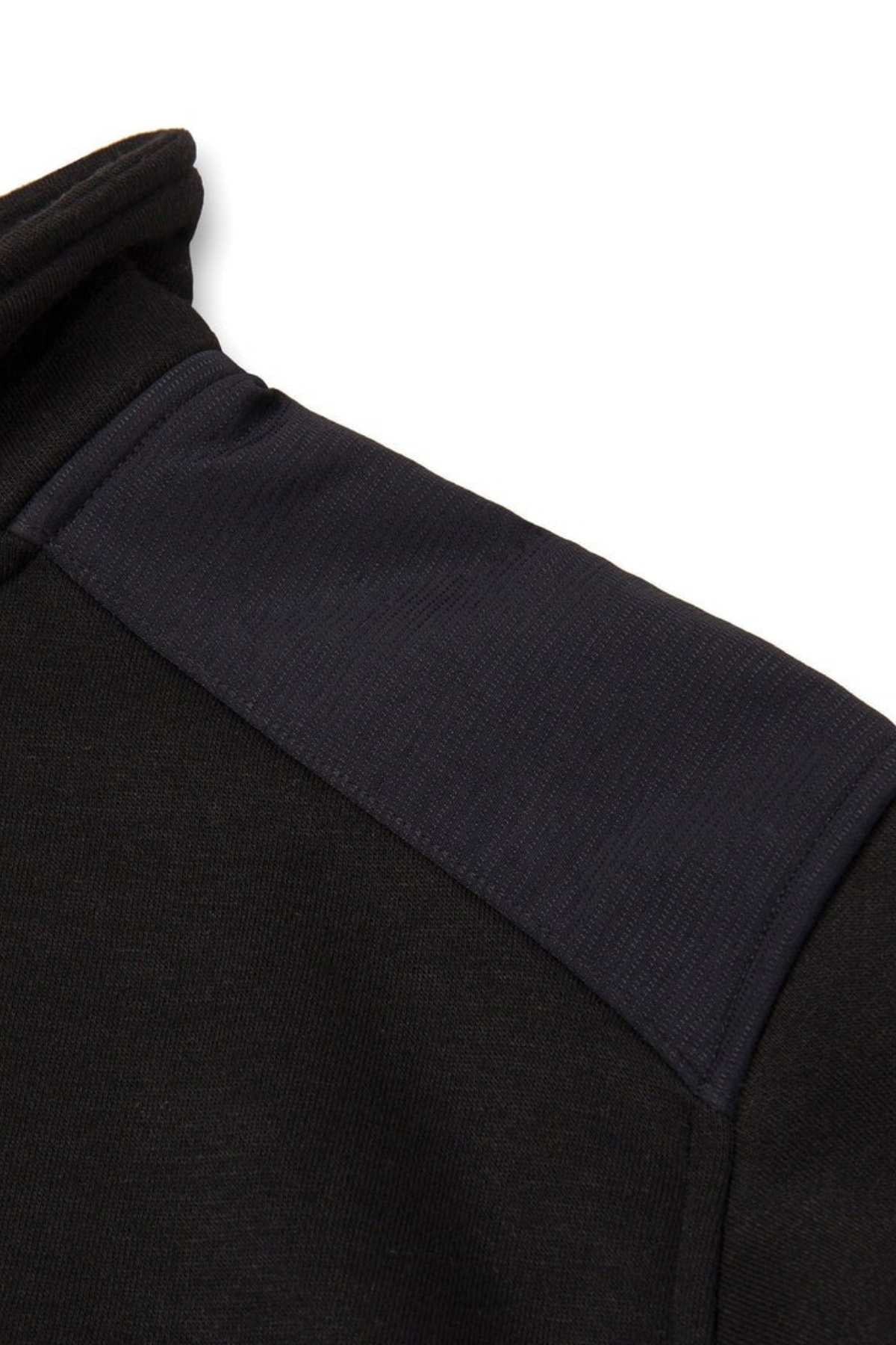 Close-up of the CAT Essential 1/4 Zip Sweatshirt's shoulder. The fabric looks soft, featuring a lighter black patch from shoulder seam to sleeve, reminiscent of warm fleece lining, offering a subtle texture and shade contrast.