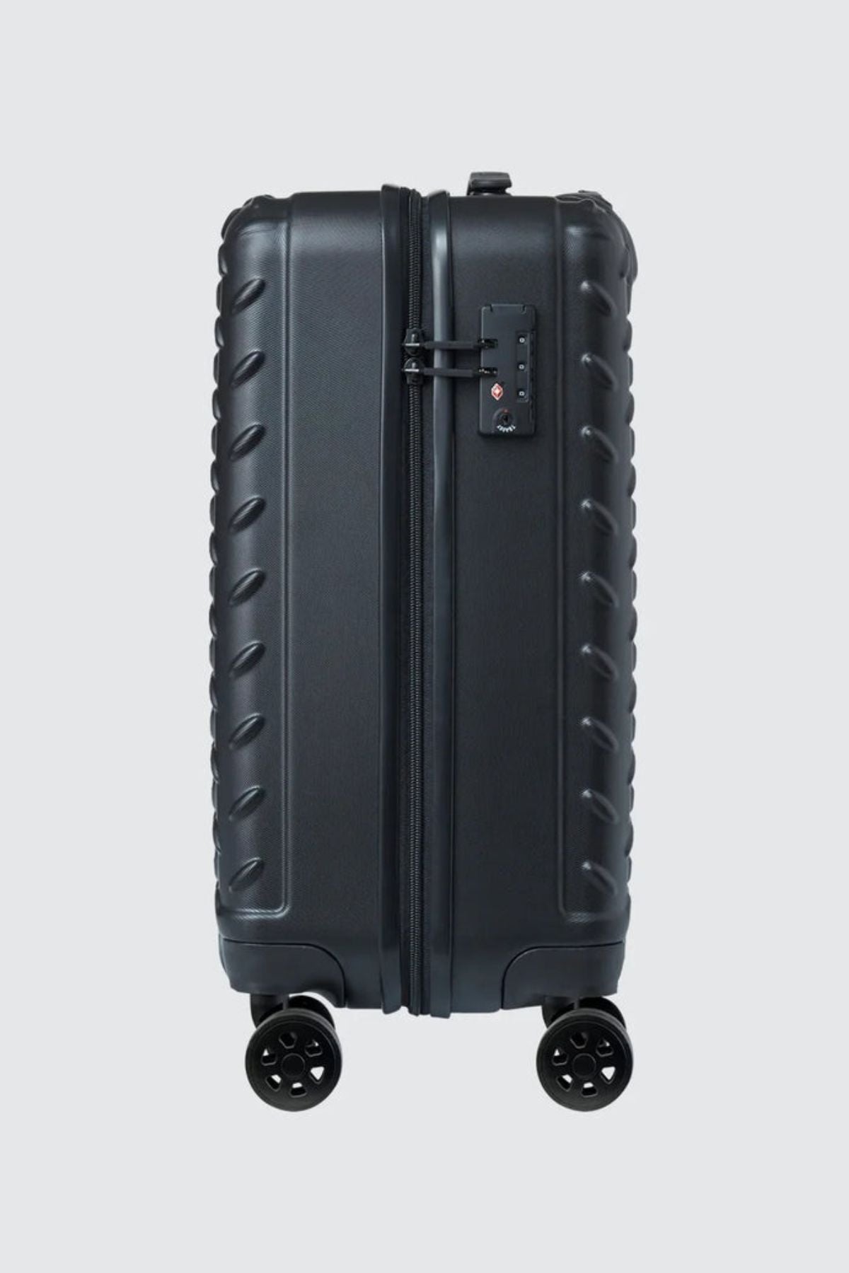 The CAT Industrial Plate 20" Trolley, a black hard-shell carry-on with a textured edge, built-in TSA lock at the top, and four wheels, stands upright against a plain light gray background.