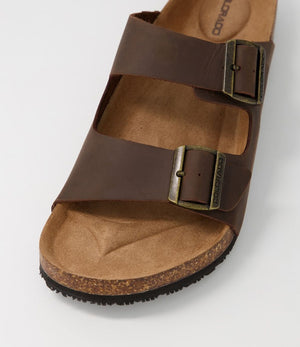 A close-up of the Colorado Karra Crazyhorse Slide, a brown leather sandal with two adjustable metal buckles and a cork sole for comfort, shown on a white background.