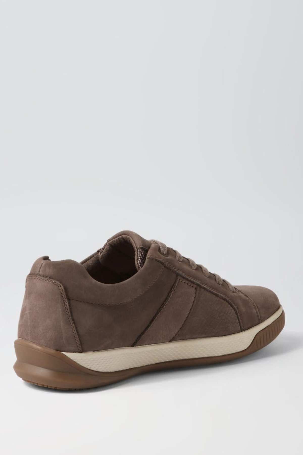 A single Colorado Edo Sneaker, featuring a brown suede-like material with stitching details, a white and brown sole, and laces, is shown from an angle highlighting both the side and back. The minimalist design of the casual shoe stands out against a plain, light-colored background.