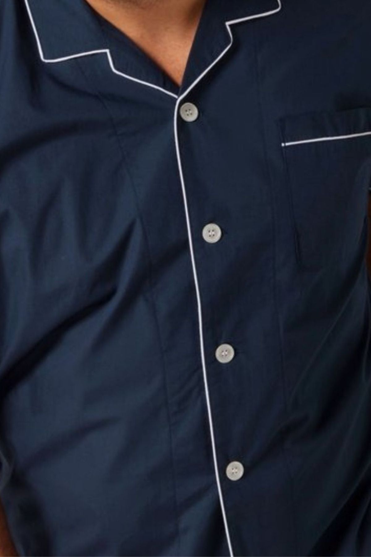 Someone wearing the Contare Country Cotton Rich Short Sleeve Classic Set in dark blue with white piping, visible from chest to neck, highlights a timeless cotton-rich sleepwear style.