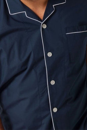 Someone wearing the Contare Country Cotton Rich Short Sleeve Classic Set in dark blue with white piping, visible from chest to neck, highlights a timeless cotton-rich sleepwear style.