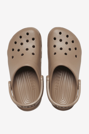 A pair of Crocs Classic Clog in beige, featuring ventilation ports on the upper and sling-back straps. The top-down view image showcases the textured insoles designed for comfort.