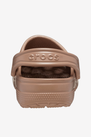 The image displays the back view of a single Crocs Classic Clog in brown. This footwear features a textured sole, ventilation ports for enhanced breathability, a rear strap embossed with "Crocs," and a non-slip tread pattern on the bottom, making it ideal for any water adventure.