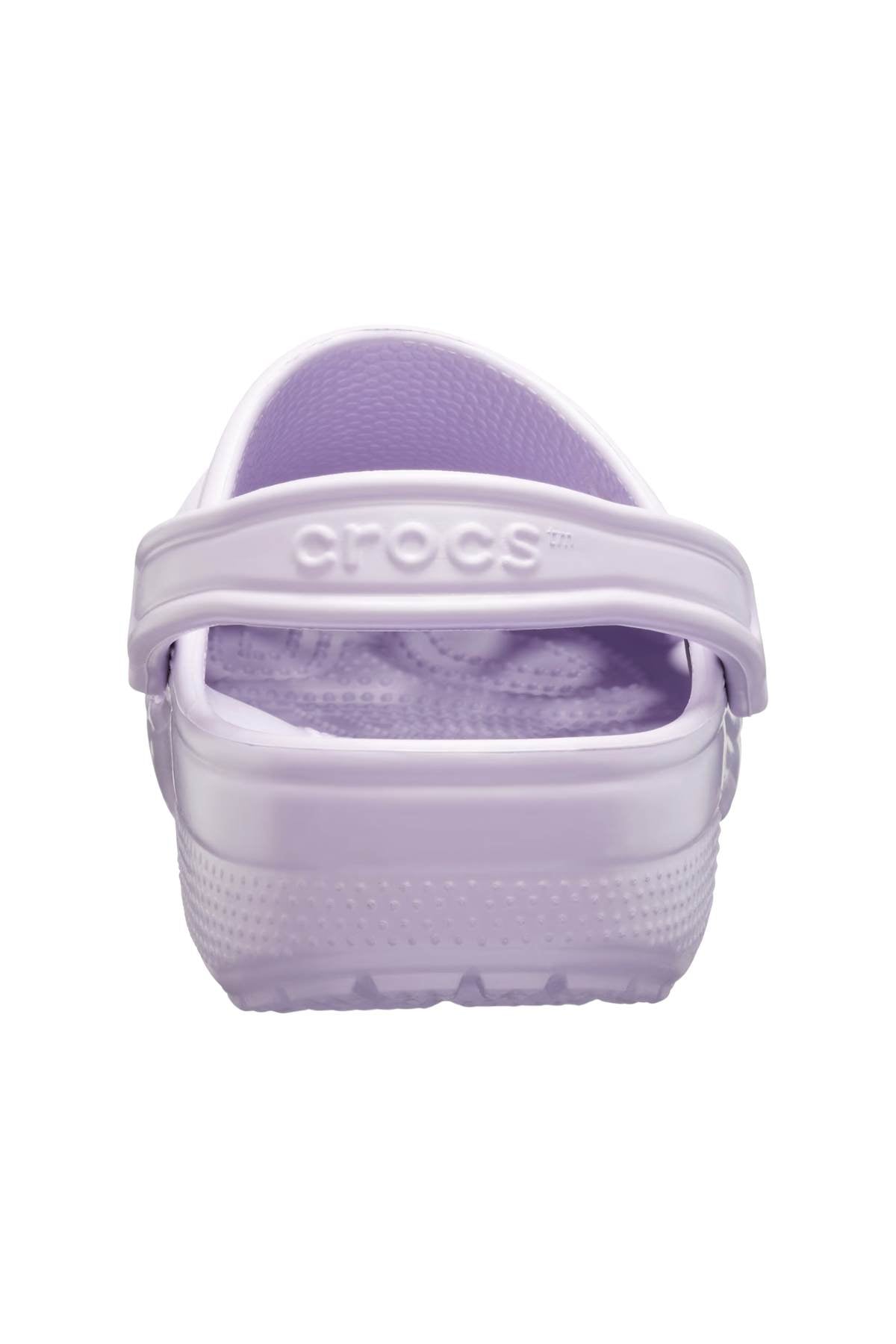 Seen from behind, a lavender Crocs Classic Kids Clog is highlighted, featuring the well-known Crocs Comfort™ and Croslite™ material. It includes a textured sole and an adjustable heel strap embossed with the Crocs brand name.