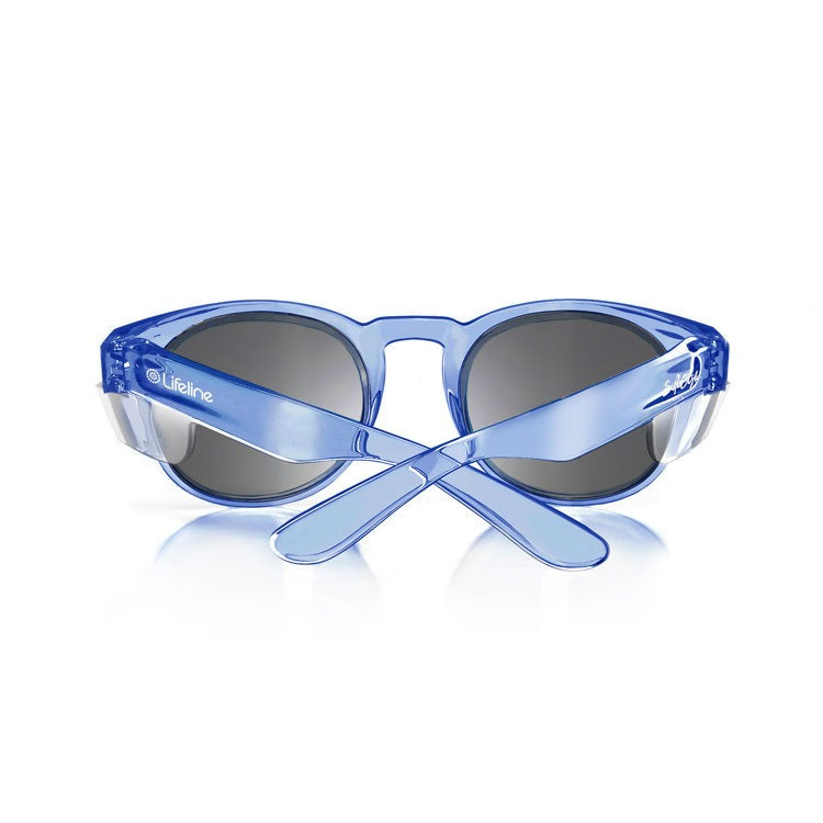 A pair of SafeStyle Cruisers Blue Frame Tinted Lens sunglasses, featuring blue translucent polycarbonate frames and dark lenses, is shown from the back with crossed arms. The "Lifeline" brand name appears on the left arm.