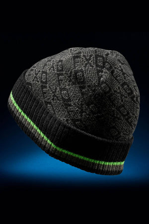 The FXD CP-11 Jacquard Beanie, in dark gray with a subtle pattern, features a ribbed black brim and a thin neon green stripe near the base. Displayed on a dark blue gradient background, this stylish winter hat is made from 100% acrylic.