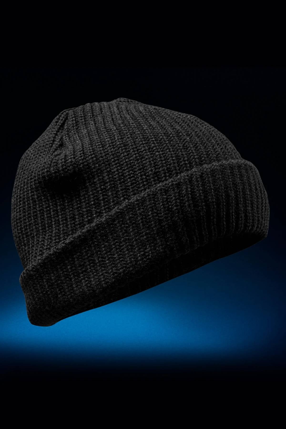 The FXD CP-10 Knit Ribbed Beanie in black, crafted from 100% acrylic with a folded brim, is displayed against a dark blue and black gradient background.