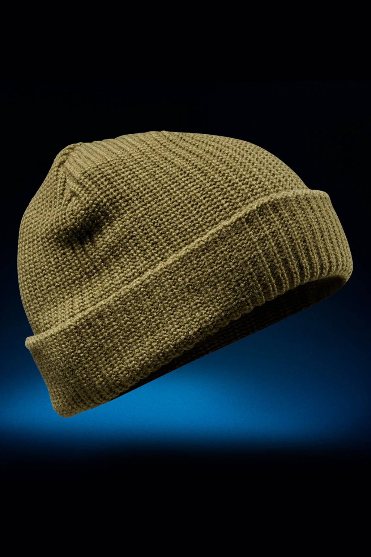 The FXD CP-10 Knit Ribbed Beanie, shown in khaki against a dark blue gradient background, features 100% acrylic fabric with a double knit layer and folded brim.