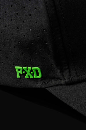 Close-up of the FXD CP-12 Tech Baseball Cap in black, made from quick-drying polyester with small perforations and bold green "FXD" lettering on the fabric.