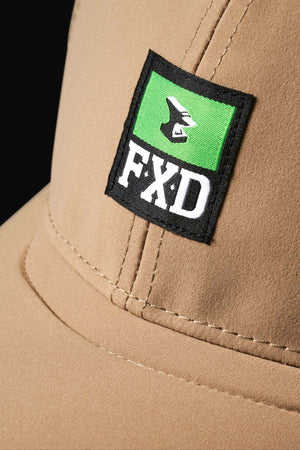 Close-up of the FXD CP-12 Tech Baseball Cap, a beige adjustable snap-back with a rectangular patch displaying the white stylized FXD logo on a green and black background, and "FXD" embroidered on the front.