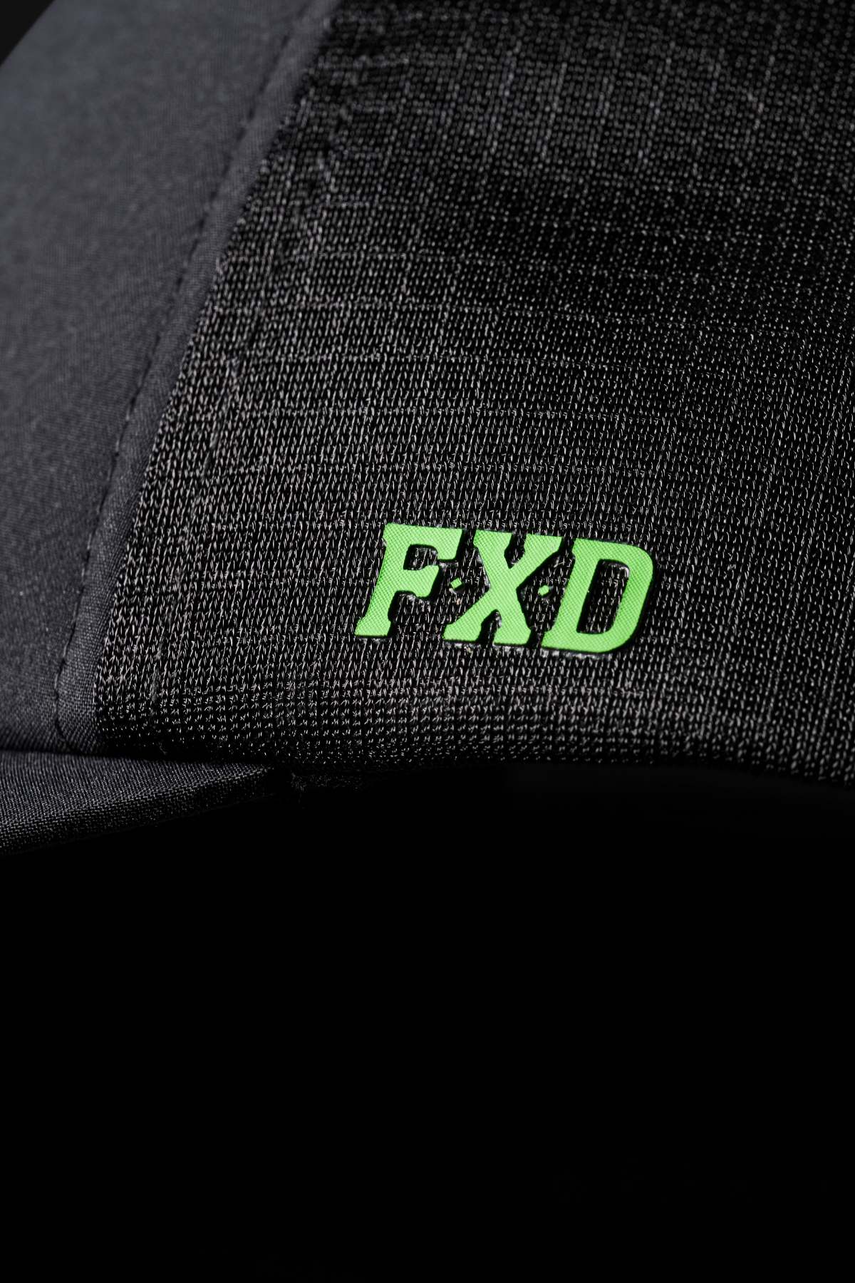 Close-up of the FXD CP-13 Trucker Cap in black with "FXD" embroidered in bright green on breathable fabric, showcasing the detailed stitching and textured material.